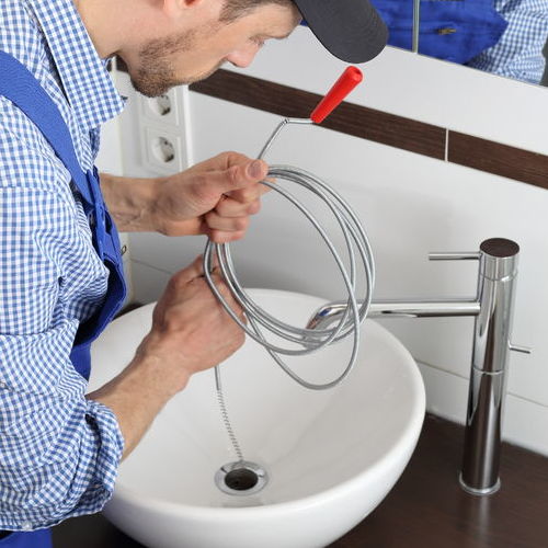 Plumber uses a drain snake for drain cleaning.
